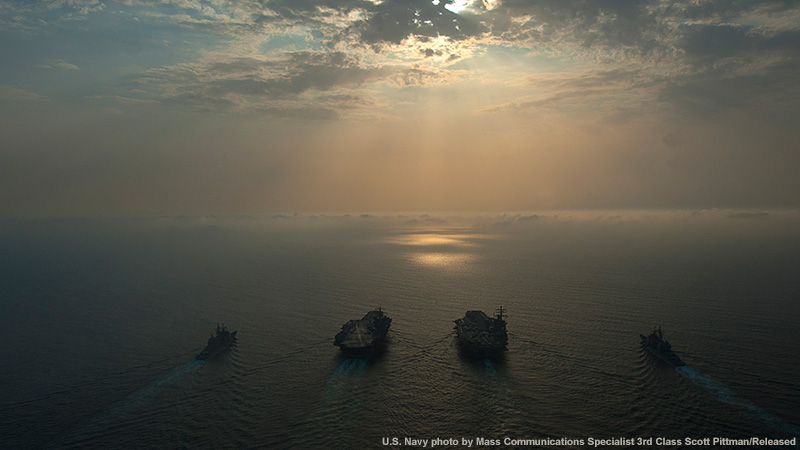 U.S. Navy photo of seas at sea with Sun shining through clouds