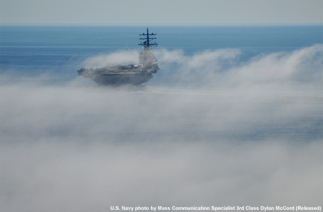 photo of Navy carrier approaching an area of fog over the water