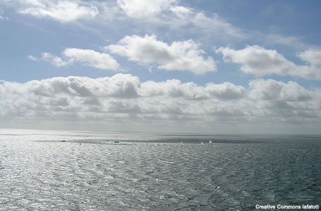 photo of sea and sky  on a day with cumulus cloud present