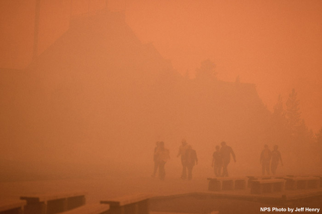 Silhouette of Old Faithful Inn and people through dense black smoke